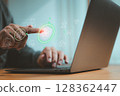 Business person interacting with cybersecurity interface on laptop. Futuristic concept of network protection, data encryption, and cloud business technology. 128362447