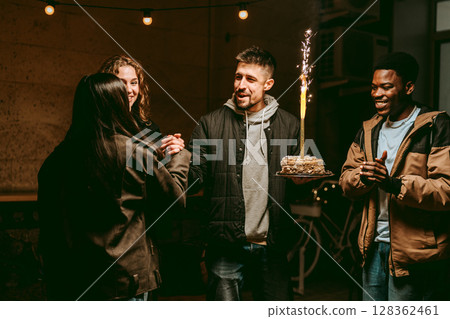 Friends celebrate a birthday with cake and laughter during an evening gathering at a cozy venue Friends celebrate a birthday with cake and laughter during an evening gathering at a cozy venue 128362461