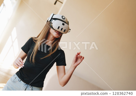 Young woman enjoys virtual reality experience in modern indoor space during afternoon hours 128362740