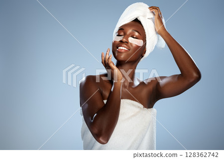 Woman enjoying a spa treatment with facial patches and towel wrapped around her hair 128362742