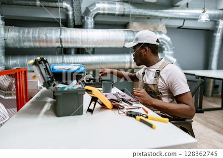 Skilled technician works on electrical tools in a modern workshop during daylight hours 128362745