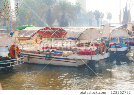 Colorful boats resting on a tranquil river under palm trees in a sunny afternoon 128362752