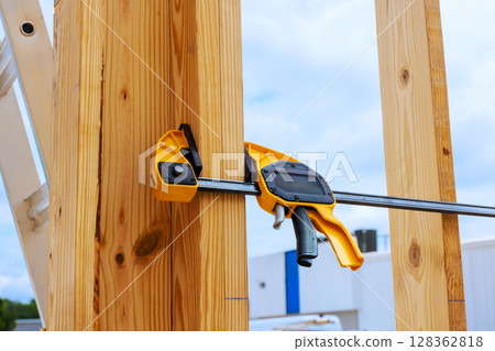 Woodworking clamp secures wooden beams together on construction site as under works day 128362818