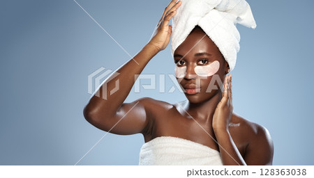 Woman applying skincare mask with towel on head in a minimalist studio setting Woman applying skincare mask with towel on head in a minimalist studio setting 128363038