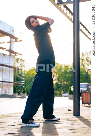 Female model poses in casual outfit during golden hour outdoors at a construction site Female model poses in casual outfit during golden hour outdoors at a construction site 128363046
