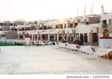 Modern resort complex features stylish architecture and outdoor seating area in sunny location Modern resort complex features stylish architecture and outdoor seating area in sunny location 128363048