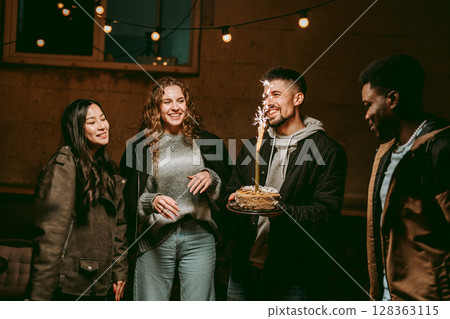 Celebrating a birthday at night with friends while enjoying cake and sparklers outdoors 128363115