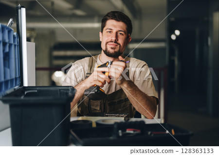Skilled worker operating power tools in workshop setting during afternoon hours 128363133