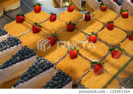 Delicious dessert display featuring strawberry and blueberry cakes in a bakery Delicious dessert display featuring strawberry and blueberry cakes in a bakery 128363164