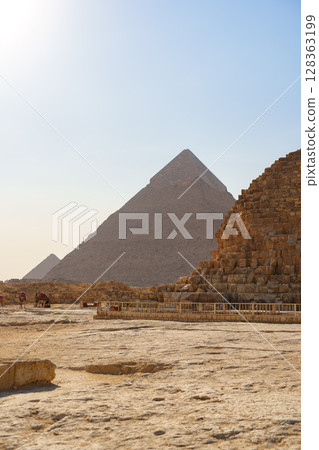 Stunning view of ancient pyramids at Giza under bright blue sky during daytime Stunning view of ancient pyramids at Giza under bright blue sky during daytime 128363199