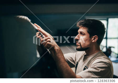 Skilled artisan working meticulously on a detailed project in a well-lit workshop space 128363306