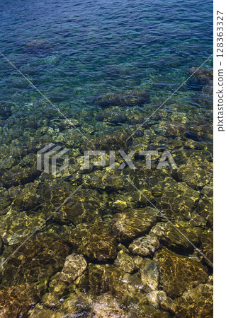 陽光下的海洋、礁石和清澈的水浪 128363327