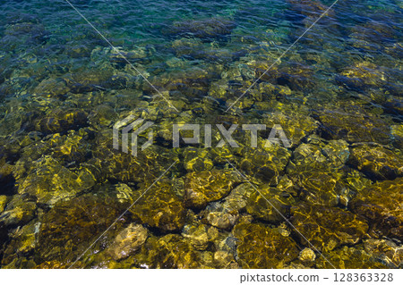 Ocean under sunlight, reef stones and clear water waves 128363328