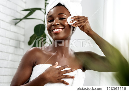 Woman performing skincare routine in a bright and modern bathroom during the day 128363336