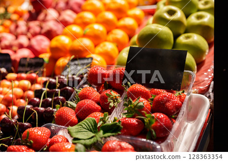 Fresh fruit display featuring strawberries, cherries, oranges, and apples at a vibrant farmers market 128363354
