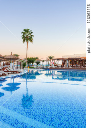 Relaxing atmosphere at a tranquil poolside retreat during golden hour 128363358