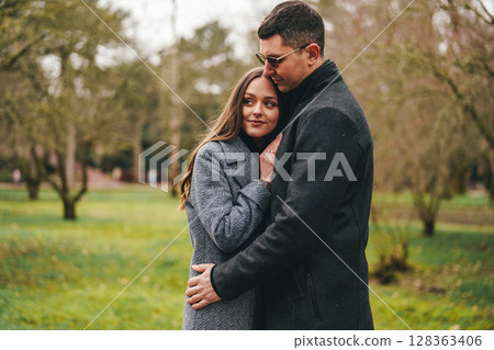 Couple enjoys intimate moment together in a serene park during a cool afternoon Couple enjoys intimate moment together in a serene park during a cool afternoon 128363406