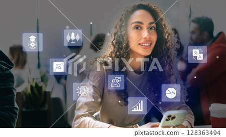 Young woman using smartphone with digital icons in a modern cafe during a busy afternoon 128363494
