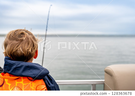 Youth caucasian boy looking out over a body of water while fishing  128363678