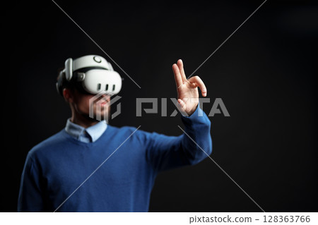 Person engaged in virtual reality experience while using motion controls indoors Person engaged in virtual reality experience while using motion controls indoors 128363766