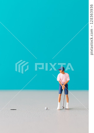 Miniature figurine of a golfer preparing to swing on a vibrant blue background. Miniature figurine of a golfer preparing to swing on a vibrant blue background. 128363936