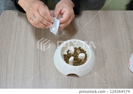 Topping dog food with green-lipped mussel supplements and preventative medicine (for fleas, ticks, and heartworms) 128364574