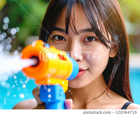 Young woman playing with a water gun 128364719