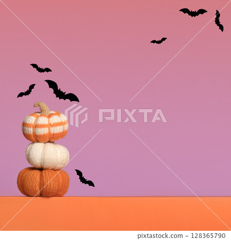 Knitted orange pumpkins with black bats on purple orange gradient background, autumn composition, front view. Halloween concept. Knitted orange pumpkins with black bats on purple orange gradient background, autumn composition, front view. Halloween concept. 128365790