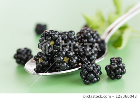A bunch of ripe blackberries in macro format on a green background 128366048