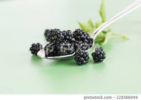 A bunch of ripe blackberries in macro format on a green background 128366049