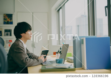 Young man doing desk work 128366196