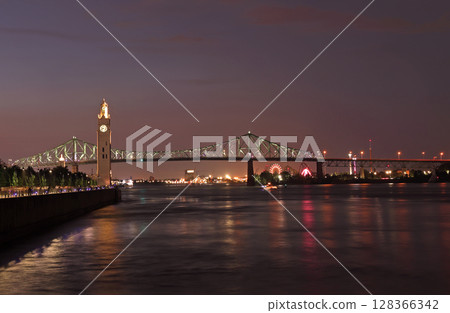 Clock Tower and Jacques Cartier Bridge over the Saint Lawrence River, illuminated at night in Montreal, Canada 128366342