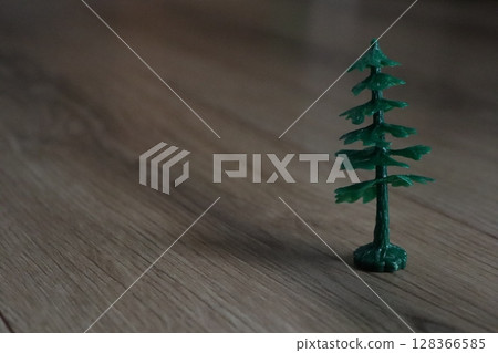 A Miniature Green Pine Tree Placed on a Wooden Floor, Perfect for Indoor Decoration 128366585