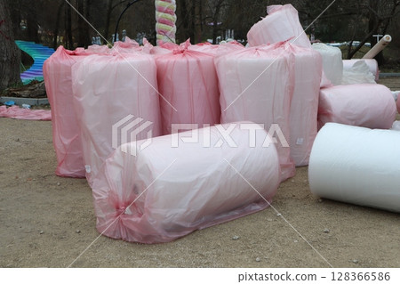 Varieties of Rolled Materials Adorned and Wrapped in Bright Pink Plastic Sheeting for Protection 128366586