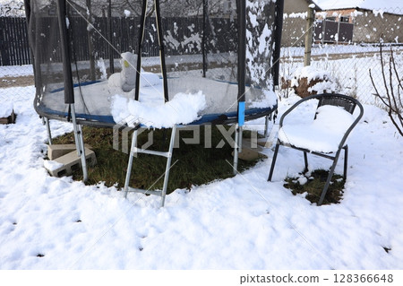 A Snow Covered Trampoline Resting in a Beautiful Winter Landscape During the Cold Season 128366648