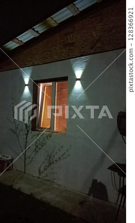 An illuminated exterior wall with a charming window at night enhances the architecture An illuminated exterior wall with a charming window at night enhances the architecture 128366921