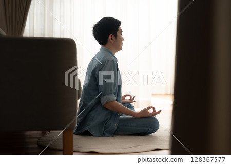 Happy young Asian man practicing yoga and meditation at home Happy young Asian man practicing yoga and meditation at home 128367577