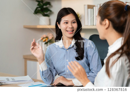 Business Strategy Discussion. Female professionals sharing ideas and data analysis in office setting. 128367816