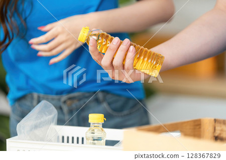 Donation and Food Sharing. Volunteer holding cooking oil for community food drive. Donation and Food Sharing. Volunteer holding cooking oil for community food drive. 128367829