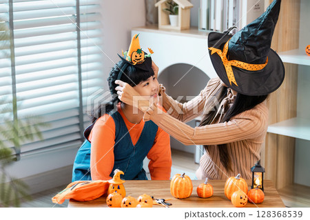 Mother and Daughter Celebrating Halloween with Witch Hat and Pumpkin Decoration at Home Mother and Daughter Celebrating Halloween with Witch Hat and Pumpkin Decoration at Home 128368539