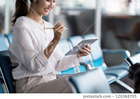 Business Professional Using Tablet at Modern Airport Terminal for Work and Communication 128368705