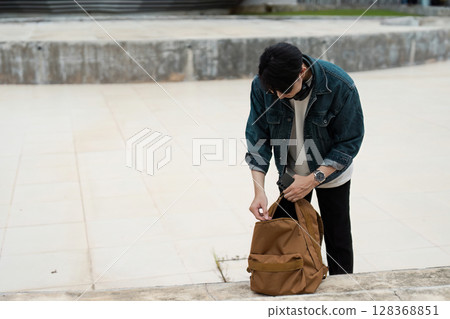 Young Traveler Preparing Backpack for Adventure in Urban Setting Young Traveler Preparing Backpack for Adventure in Urban Setting 128368851
