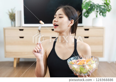 Young Woman Enjoying a Healthy Salad at Home Promoting Wellness and Healthy Living 128368886
