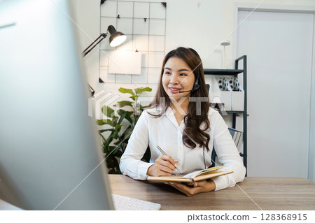 Smiling Call Center Agent with Headset Working at Desk in Modern Office Environment 128368915
