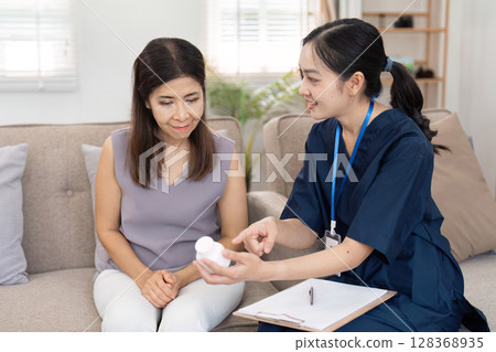 Healthcare Professional Assisting Patient at Home with Medication Guidance in a Comfortable Living Room Setting Healthcare Professional Assisting Patient at Home with Medication Guidance in a Comfortable Living Room Setting 128368935