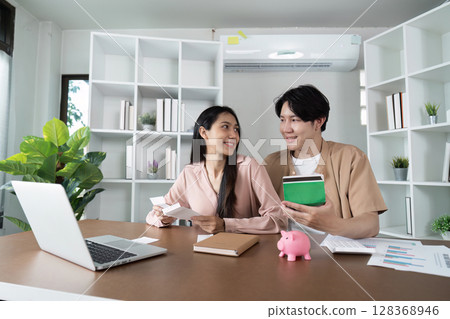 Young Couple Discussing Savings and Financial Planning with Piggy Bank and Documents in Modern Home Office Young Couple Discussing Savings and Financial Planning with Piggy Bank and Documents in Modern Home Office 128368946
