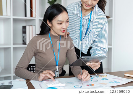 Professional Business women collaboration on Financial Reports and Digital Tablet in Modern Office Setting 128369030