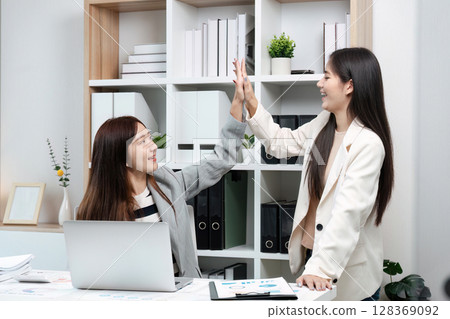 colleagues Businesswomen Celebrating Success with a High Five in a Modern Office Environment 128369092