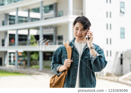 College Student Talking on Phone Outdoors with Backpack in Modern Campus Setting College Student Talking on Phone Outdoors with Backpack in Modern Campus Setting 128369096