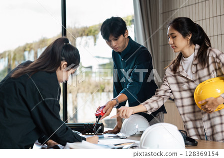 Architect Collaborating on Construction Project in Modern Office with Safety Helmet and Blueprint 128369154